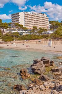 un gran edificio en una playa con rocas en el agua en Universal Hotel Lido Park & Spa, en Paguera
