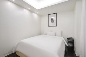 a white bedroom with a white bed and a ceiling at Show Hotel in Pyeongtaek