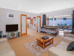 a living room with a couch and a tv at Sunset View - Pauanui Waterfront Home in Pauanui