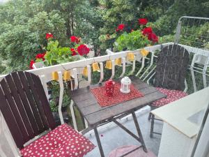 een tafel en stoelen op een balkon met rode bloemen bij Sirob bubanj in Kragujevac