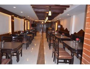 a dining room with wooden tables and chairs at Hotel Shafaaf Plaza, Srinagar in Srinagar