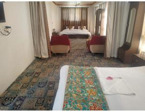 a hotel room with two beds and two chairs at Hotel Shafaaf Plaza, Srinagar in Srinagar
