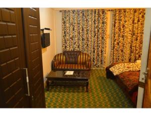 a hotel room with a chair and a bed at Hotel Shafaaf Plaza, Srinagar in Srinagar