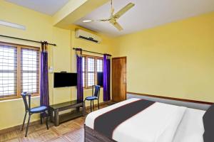 una camera con un letto, due sedie e una TV di Collection O 81056 Express Suites a Kakkayam
