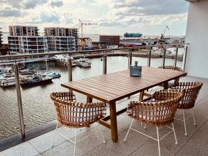 a wooden table and chairs on a balcony with a harbor at COAST HOUSE Seaside Loft in Bremerhaven