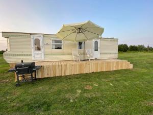 a mobile home with an umbrella and a grill at Nature&Rest in Łąck