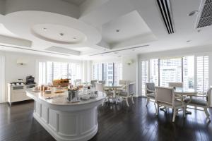 een witte kamer met tafels, stoelen en ramen bij Cape House Langsuan Hotel in Bangkok