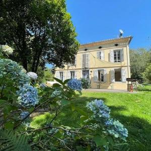 una casa grande con flores azules en el patio en Maison gîte tranquille et nature., en Verdun-en-Lauragais