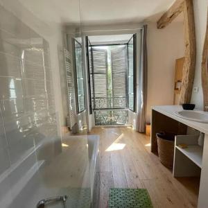 baño con bañera, lavabo y ventana en Maison gîte tranquille et nature., en Verdun-en-Lauragais