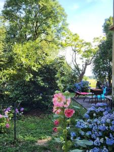 un jardín con flores, una mesa y un banco en Maison gîte tranquille et nature., en Verdun-en-Lauragais