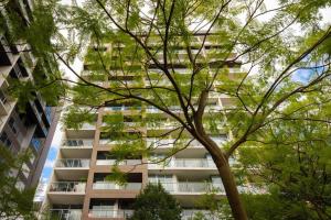 a tall building with trees in front of it at City apartment, pool & carpark in Adelaide