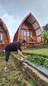 a woman standing in front of a vegetable garden in front of a house at Family rinjani bungalow in Sajang