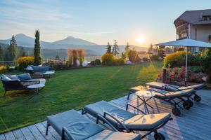 une terrasse avec des chaises longues et des tables sur une pelouse dans l'établissement Hotel Cristal, à Obereggen