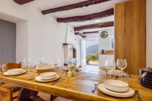 a dining room with a wooden table with wine glasses at Le Masage - Appt pour 6 vue montagne in Castagniers