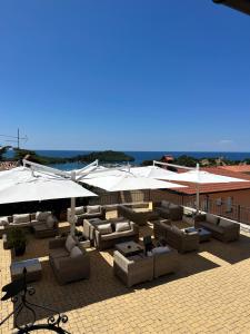 eine Terrasse mit Sofas und Sonnenschirmen auf dem Dach in der Unterkunft Hotel Vista in Vrsar