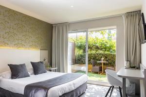 a bedroom with a bed and a desk and a window at Le Carré d'Alethius Logis Hôtel Restaurant in Charmes-sur-Rhône