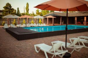Eine Gruppe von Stühlen und Sonnenschirmen neben einem Pool in der Unterkunft REEF Hotel in Koblewe