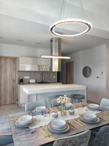 a dining room with a table with chairs and a chandelier at Paskom Apartmanház in Nyergesújfalu