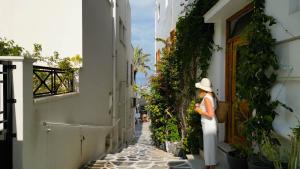 een vrouw die in een steegje uit een deur kijkt bij AMMOS at AmazeU Suites Naxos in Naxos Chora