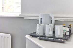 bandeja con 4 tazas de café blancas y control remoto en Properties Unique Dene Rooms - Family Room, en Newcastle