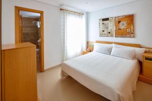 1 dormitorio con cama blanca y ventana en ECO-MANOLITA, en Elche