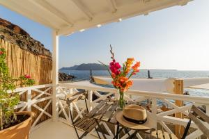 una mesa con un jarrón de flores en el balcón en The Bay - Loft apartment Sea & Sunset View, en Oia