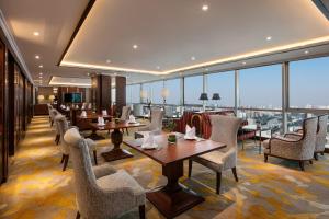 un restaurante con mesas, sillas y ventanas grandes en Sheraton Nanjing Kingsley Hotel & Towers, en Nanjing