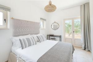 una camera bianca con un grande letto e uno specchio di Villa Solivetta a Martina Franca