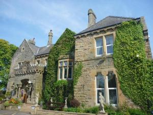 a stone house with a statue in front of it at Hunday Manor Country House Hotel in Workington