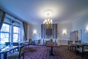 una sala da pranzo con tavoli, sedie e lampadario a braccio di Hunday Manor Country House Hotel a Workington