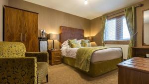 a hotel room with a bed and a chair at Hunday Manor Country House Hotel in Workington