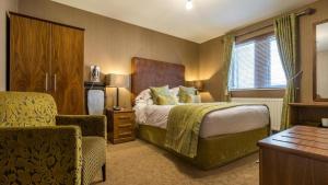 Habitación de hotel con cama y silla en Hunday Manor Country House Hotel, en Workington