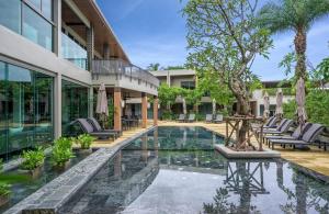 une piscine extérieure avec des chaises et un complexe dans l'établissement Fusion Suites Phuket Patong, à Patong Beach