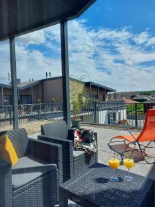 patio z krzesłami i 2 kieliszkami soku pomarańczowego w obiekcie Paskom Apartmanház w mieście Nyergesújfalu