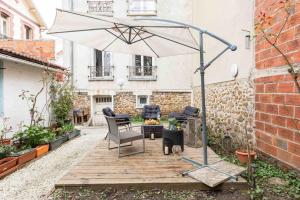 une terrasse avec un parasol, une table et des chaises dans l'établissement Jacuzzi extérieur à 15 min de Paris*, à Rosny-sous-Bois