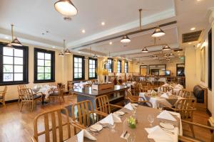 a dining room with tables and chairs and windows at Cape House Hotel, Bangkok in Bangkok