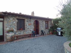 a stone house with a bench and a grill at Agriturismo Bandinacci in Santa Luce