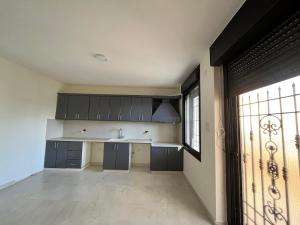 a kitchen with black cabinets and a sink and a window at German-Palestinian Appartement in Al Khalīl