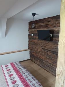 um quarto com uma parede de madeira e uma televisão de ecrã plano em AlBy&B em Arnoldstein