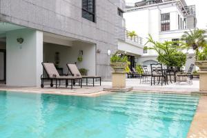 a swimming pool with chairs and a table next to a building at Cape House Langsuan Hotel in Bangkok