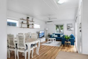 a dining room and living room with a table and chairs at Coastal Cottage Batemans Bay in Batemans Bay