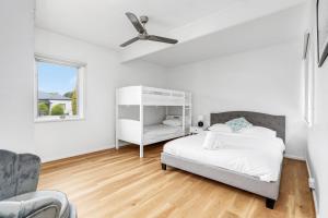 a white bedroom with a bed and a ceiling fan at Coastal Cottage Batemans Bay in Batemans Bay