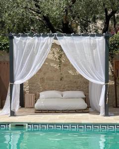 a bed sitting under a canopy next to a pool at Les jardins de Manotte in La Motte