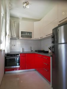 eine Küche mit roten Schränken und einem Kühlschrank aus Edelstahl in der Unterkunft Apartment Silvana in Trogir