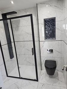 uma casa de banho com um chuveiro e um WC preto. em Luxury Room em Harold Wood