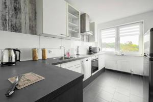 a kitchen with white cabinets and a black counter top at Top Equipped Netflix WLAN Landschaftspark in Duisburg