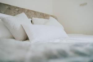 un letto bianco con quattro cuscini sopra di Linen Cottage- Parking, LEDs, 4K TVs, 5G WIFI and more! a Bath
