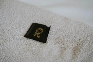 una piccola scatola nera con un simbolo d'oro su una coperta di Linen Cottage- Parking, LEDs, 4K TVs, 5G WIFI and more! a Bath