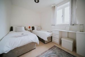 a bedroom with two beds and a desk and a window at Linen Cottage- Parking, LEDs, 4K TVs, 5G WIFI and more! in Bath