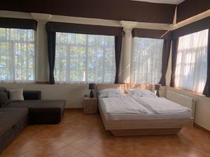 a bedroom with a bed and a couch and windows at BF Hotel in Balatonföldvár +39 photos